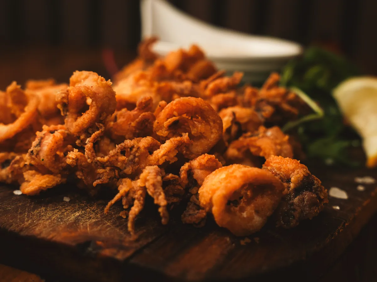 Fried calamari at STR·EAT, served on a wooden board with lemon and leaves