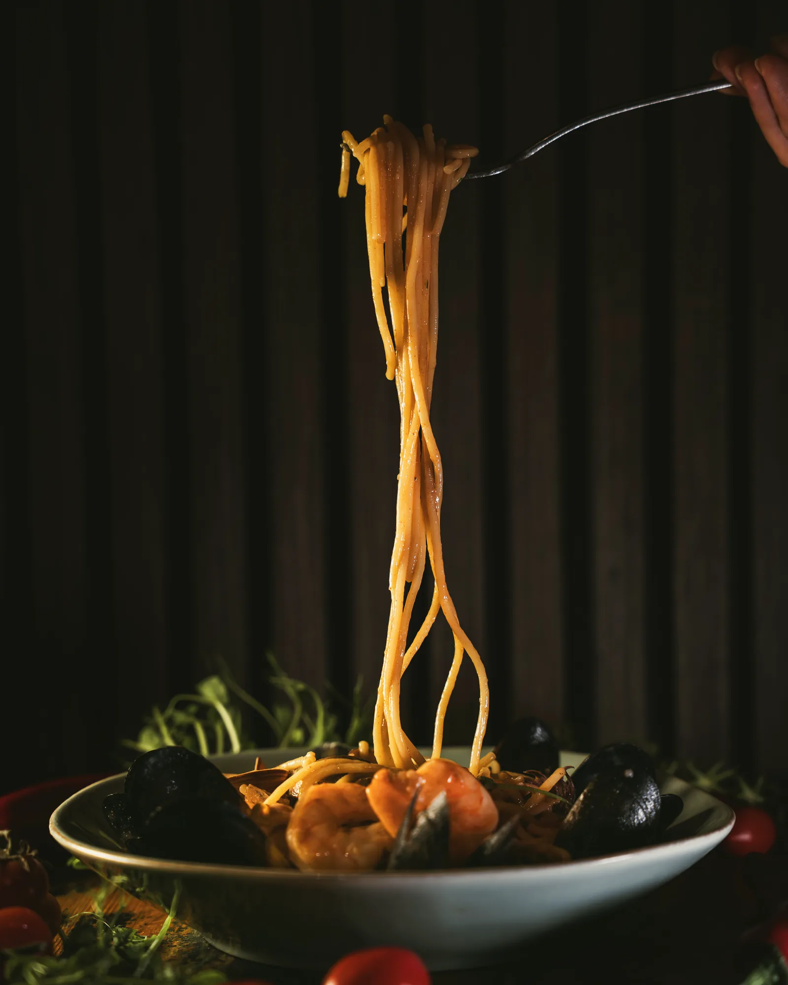 Seafood spaghetti being lifted from the bowl at STR·EAT, prawns and mussels below