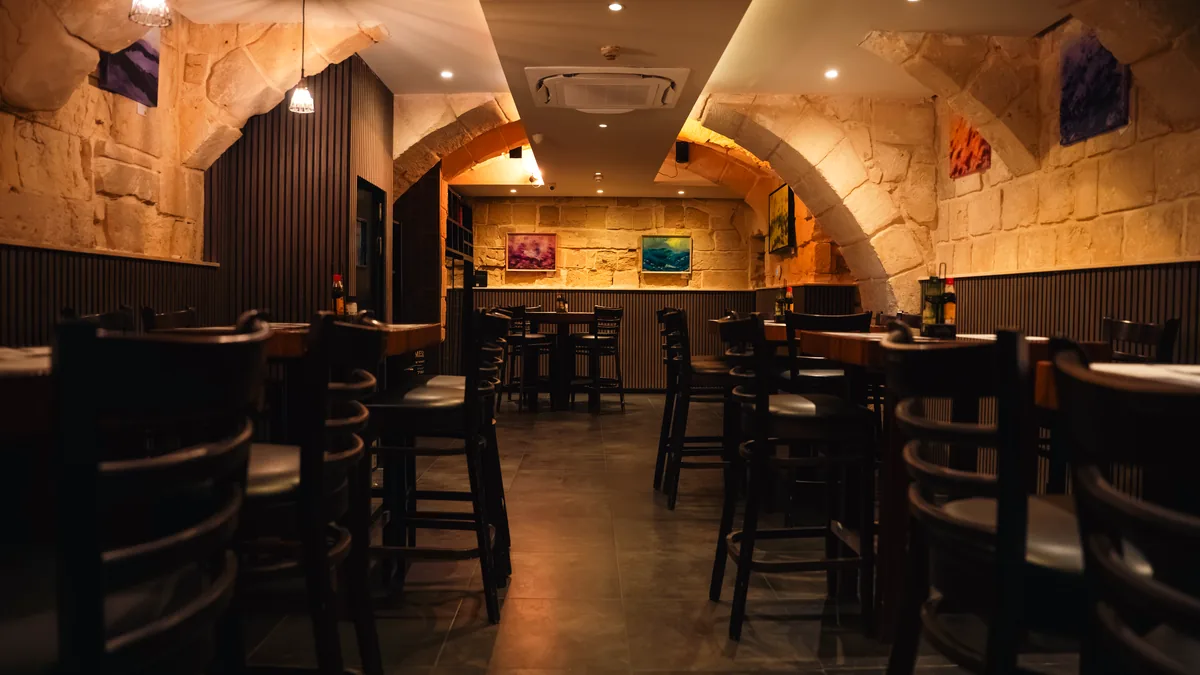 The vaulted limestone dining room at STR·EAT, tables set under stone arches and warm lamplight