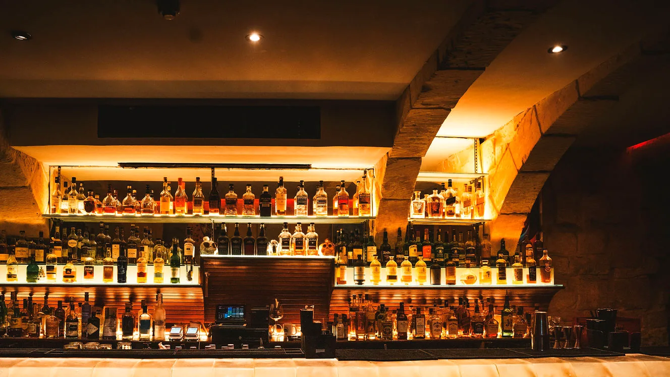 The backbar at STR·EAT, tiers of whisky bottles lit warm beneath a stone vault