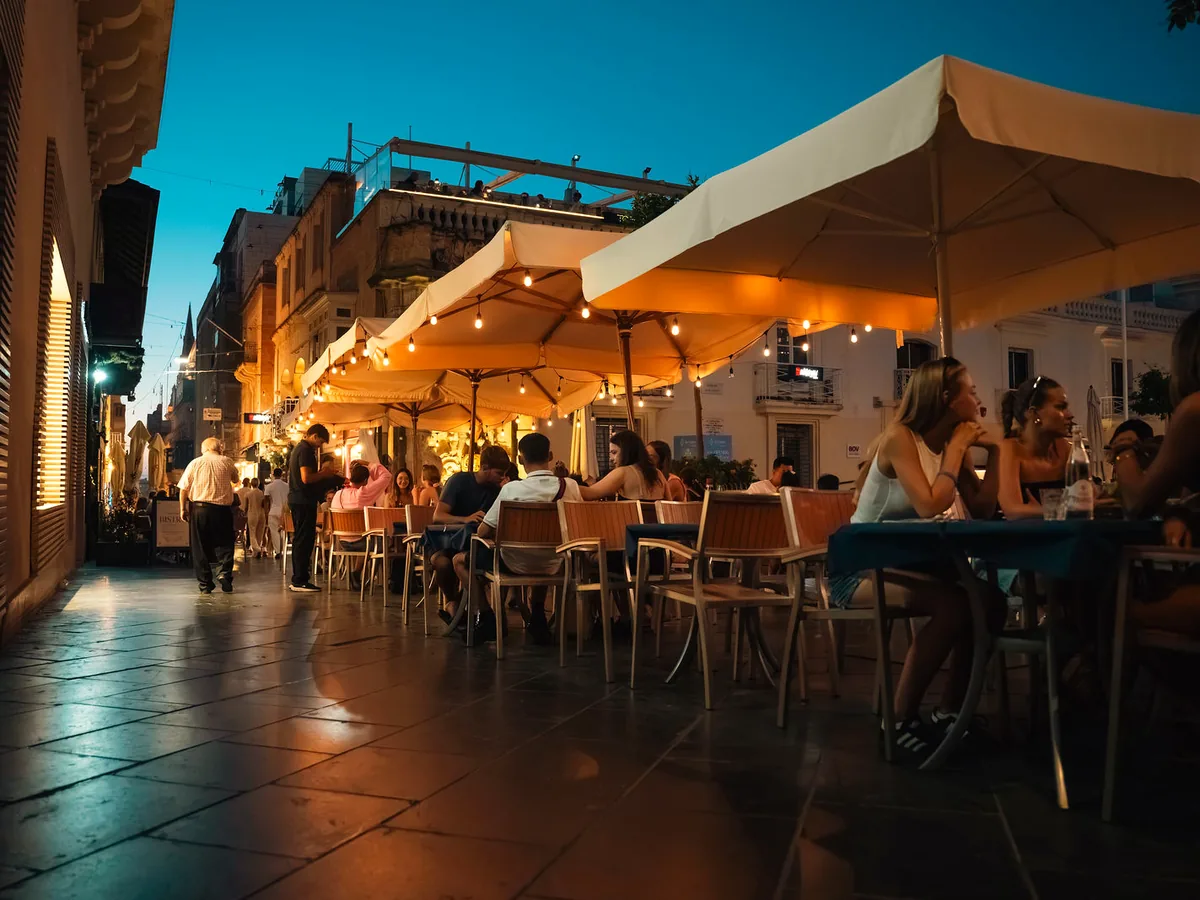 The STR·EAT terrace in the evening, tables under lit umbrellas