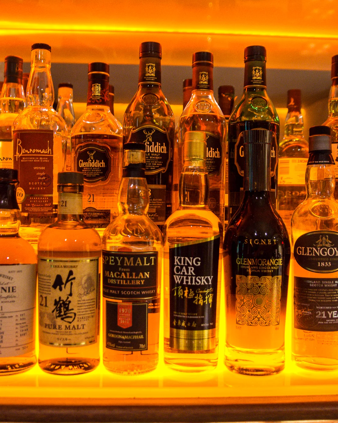A shelf of single malt whiskies at STR·EAT, Speyside, Islay, Japanese and Highland bottles side by side