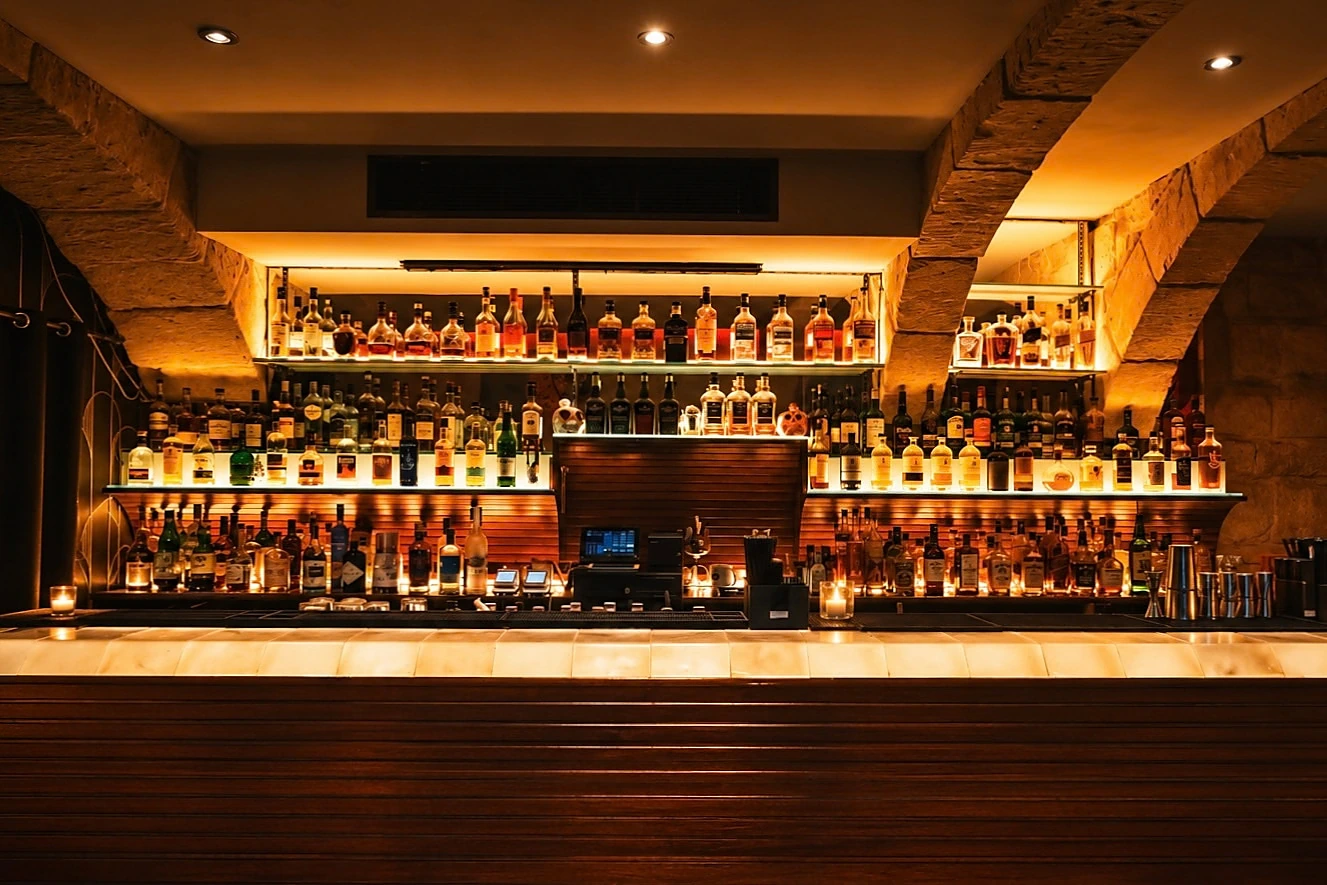 The whisky bar at STR·EAT, bottles lit warm beneath a stone vault